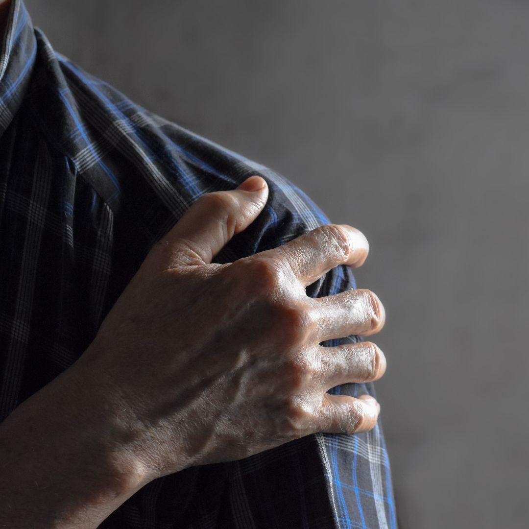 Person gripping the outside of their shoulder, showing where calcific tendinopathy pain is felt
