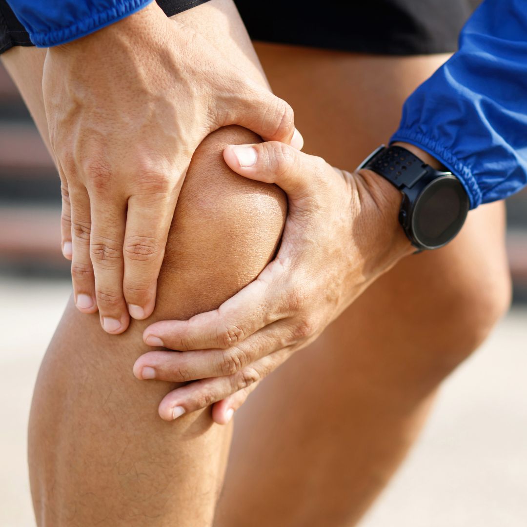 Person gripping the side of their knee along the joint line after a twisting injury, typical of a meniscus tear