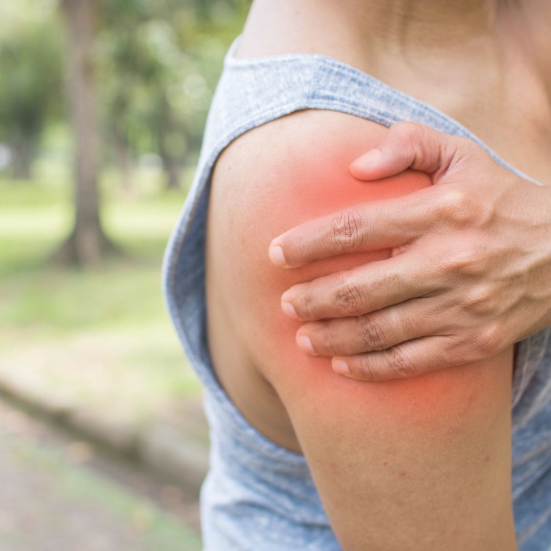 Person holding the outside of their upper arm with the shoulder highlighted, showing where rotator cuff tendinopathy pain is felt