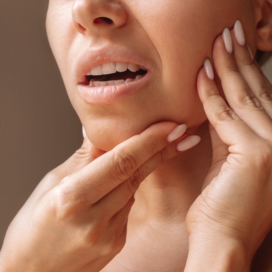 Woman holding her jaw in pain, a typical presentation of TMJ dysfunction